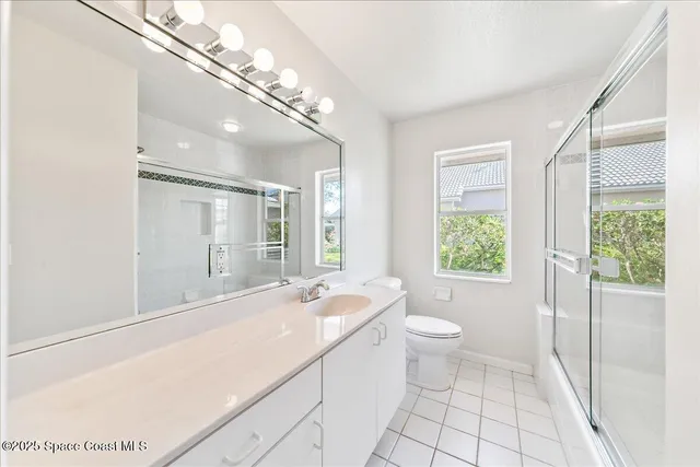 a spacious bathroom with a granite countertop sink a toilet a mirror and a tub