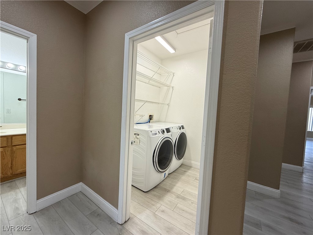 7062 Russell Ranch Avenue Las Vegas, NV 89113 - Photo 22 of 32 Laundry room with light wood-style floors, baseboards, washer and dryer, and laundry area
