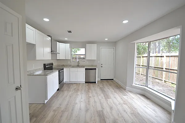 a kitchen with wooden floors a sink a window and white stainless steel appliances