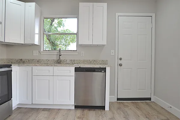 a kitchen with granite countertop white cabinets and a window