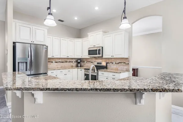 a kitchen with granite countertop a refrigerator and a stove top oven