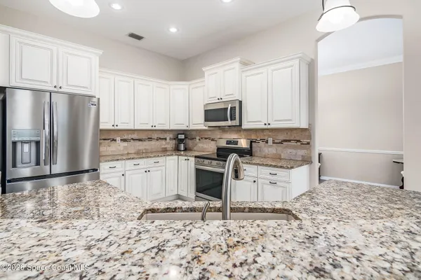a kitchen with a stove a sink and chandelier