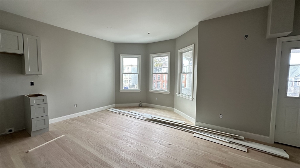 663 Columbia Road, Unit 3 Boston, MA 02125 - Photo 16 of 21 a view of an empty room with a window and wooden floor