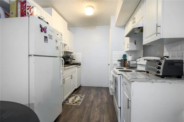 a kitchen with stainless steel appliances a refrigerator a sink a stove and white cabinets