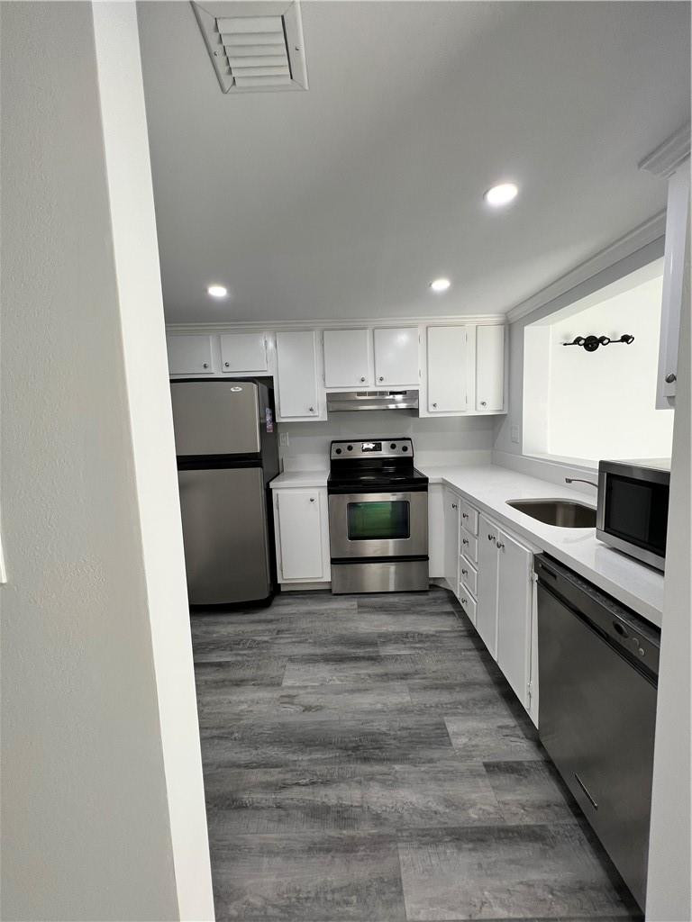 6451 North University Drive, Unit 112 Tamarac, FL 33321 - Photo 6 of 21 a large kitchen with cabinets wooden floor and stainless steel appliances