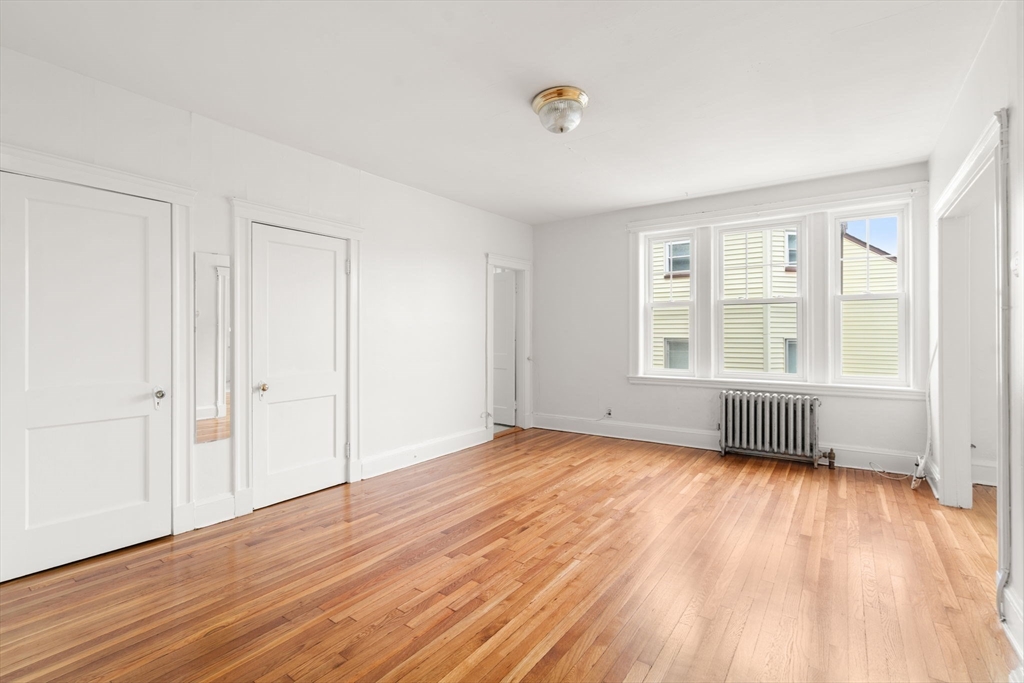 97 Chester Street, Unit 8 Boston, MA 02134 - Photo 14 of 19 an empty room with wooden floor and windows