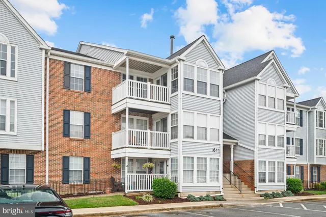 a front view of a building with lot of cars and trees