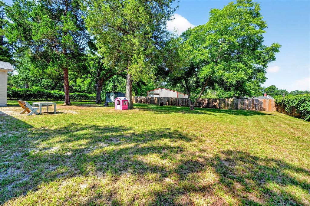 810 Edna Street Athens, TX 75751 - Photo 26 of 28 Expansive rear yard featuring mature trees, a privacy fence, and a storage shed