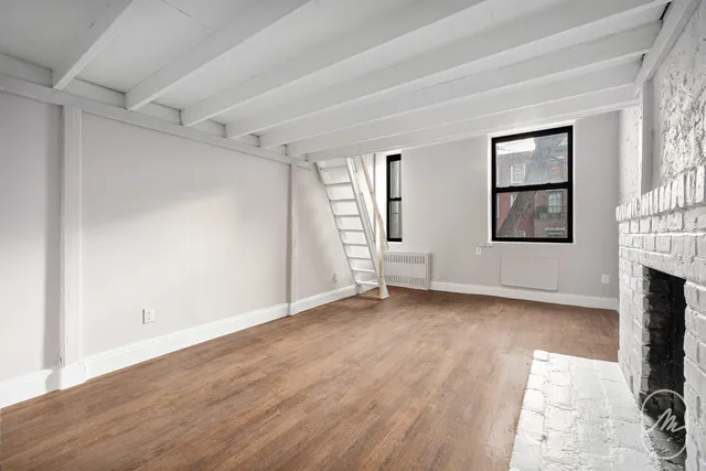 an empty room with wooden floor and fireplace