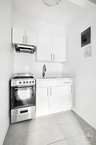 a kitchen with a refrigerator and white cabinets