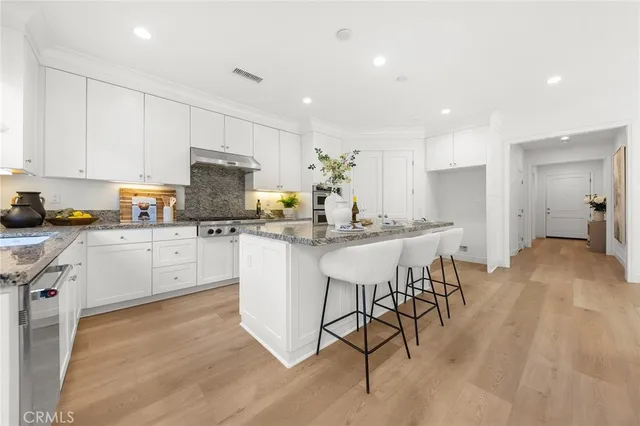 a kitchen with kitchen island granite countertop a table chairs sink and cabinets