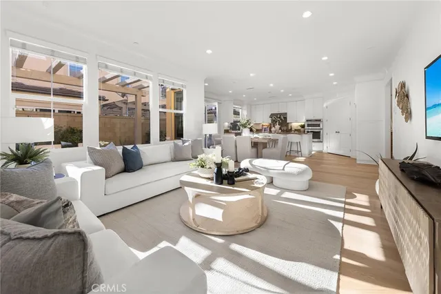 a living room with stainless steel appliances kitchen island granite countertop a table chairs and a refrigerator