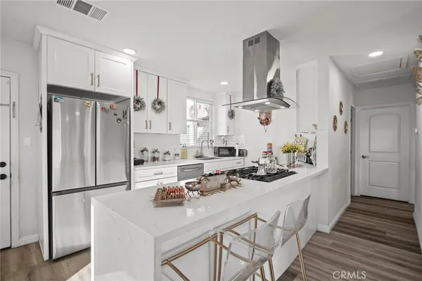 a view of a kitchen with kitchen island a sink stainless steel appliances and cabinets
