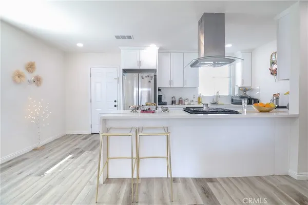a kitchen with a sink dishwasher stove and white cabinets with wooden floor