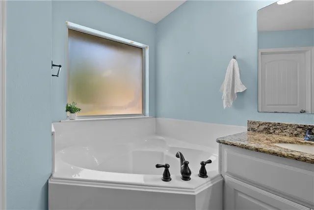 a bathroom with a granite countertop sink a large mirror and a bathtub
