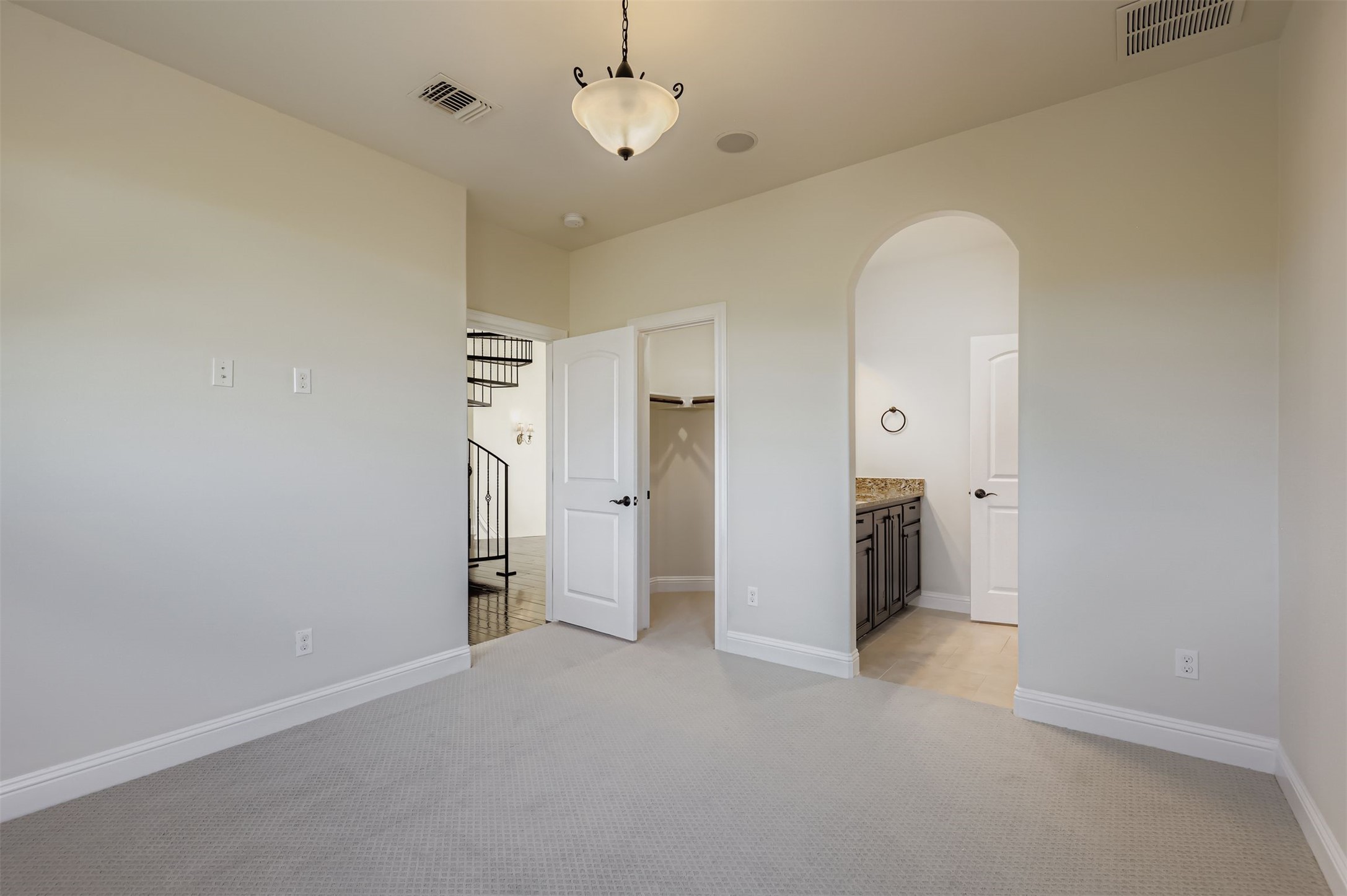 1415 Roaring Fork Leander, TX 78641 - Photo 22 of 39 Unfurnished bedroom featuring a walk in closet, arched walkways, light colored carpet, and ensuite bath