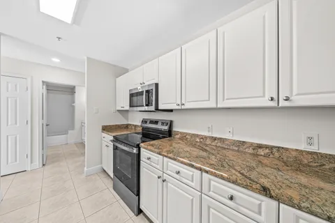 a kitchen with granite countertop white cabinets and stainless steel appliances