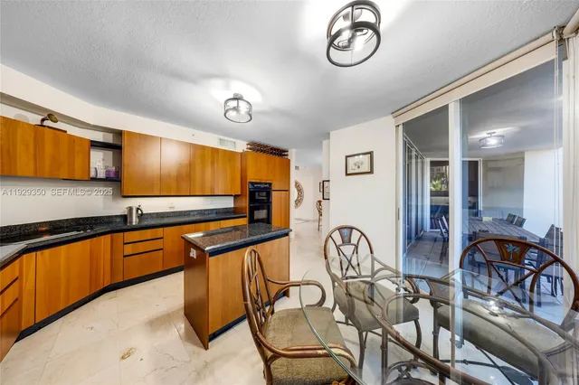a very nice looking kitchen with granite countertop a stove a sink cabinets and a large window