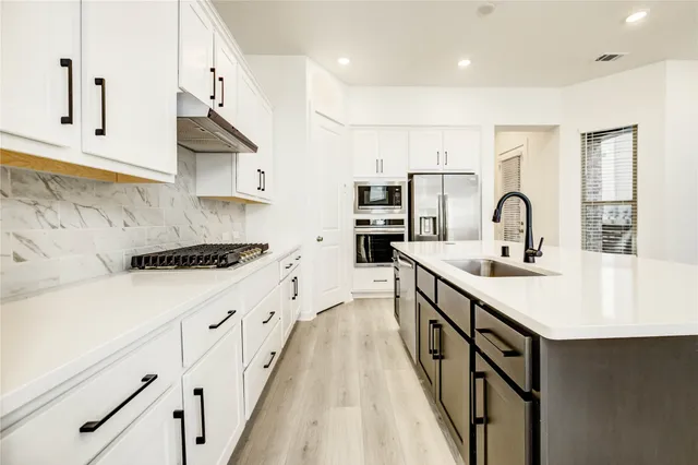 a kitchen with kitchen island granite countertop a sink stove and cabinets