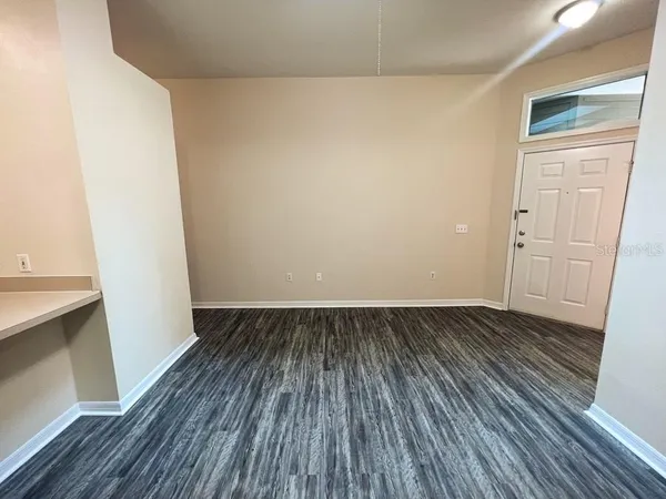 a view of an empty room with wooden floor and closet