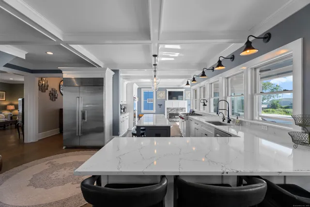 a large white kitchen with a large window and stainless steel appliances