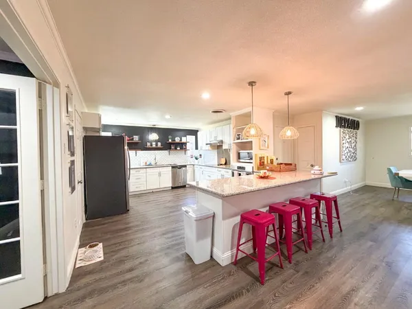 a kitchen with refrigerator and wooden floor