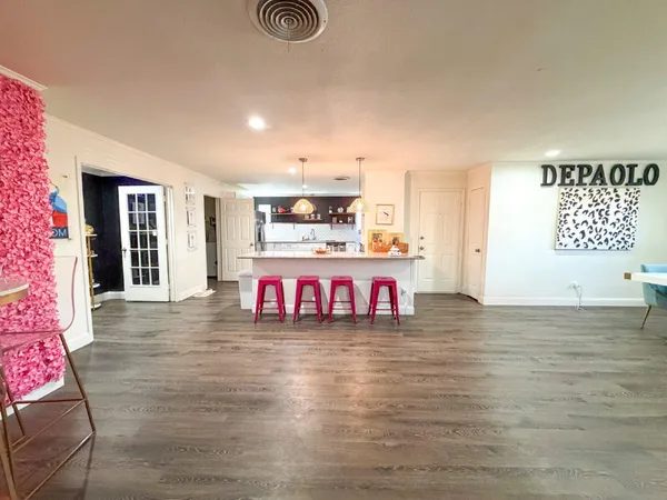 a living room with stainless steel appliances kitchen island granite countertop a couch and a dining table with wooden floor