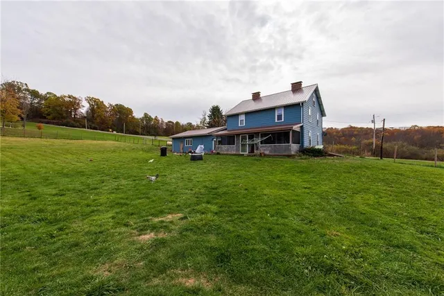 a view of a house with a big yard and large trees