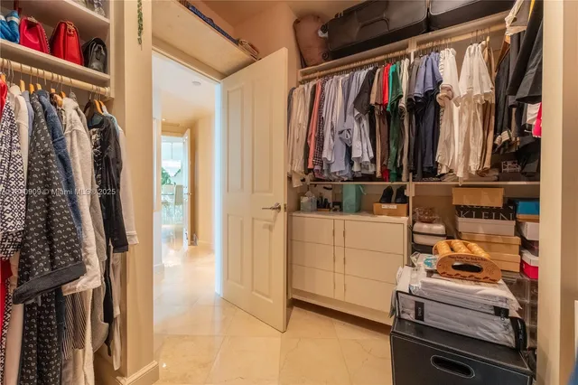 a view of walk in closet with clothes and shoes