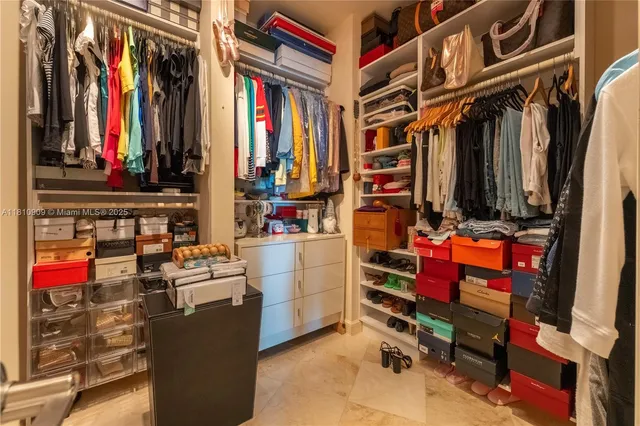 a view of walk in closet with clothes and shoes