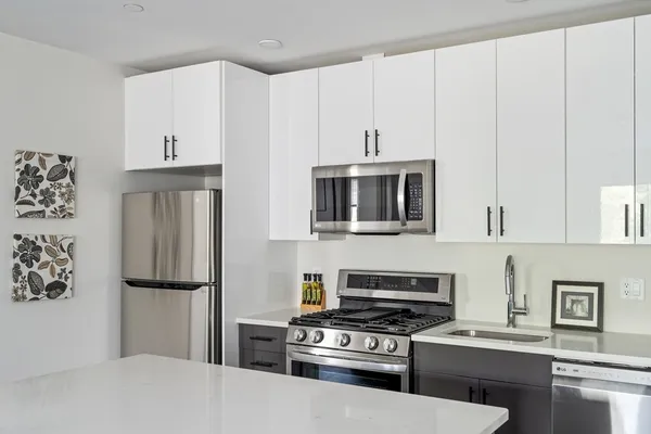a kitchen with stainless steel appliances a refrigerator a stove and white cabinets