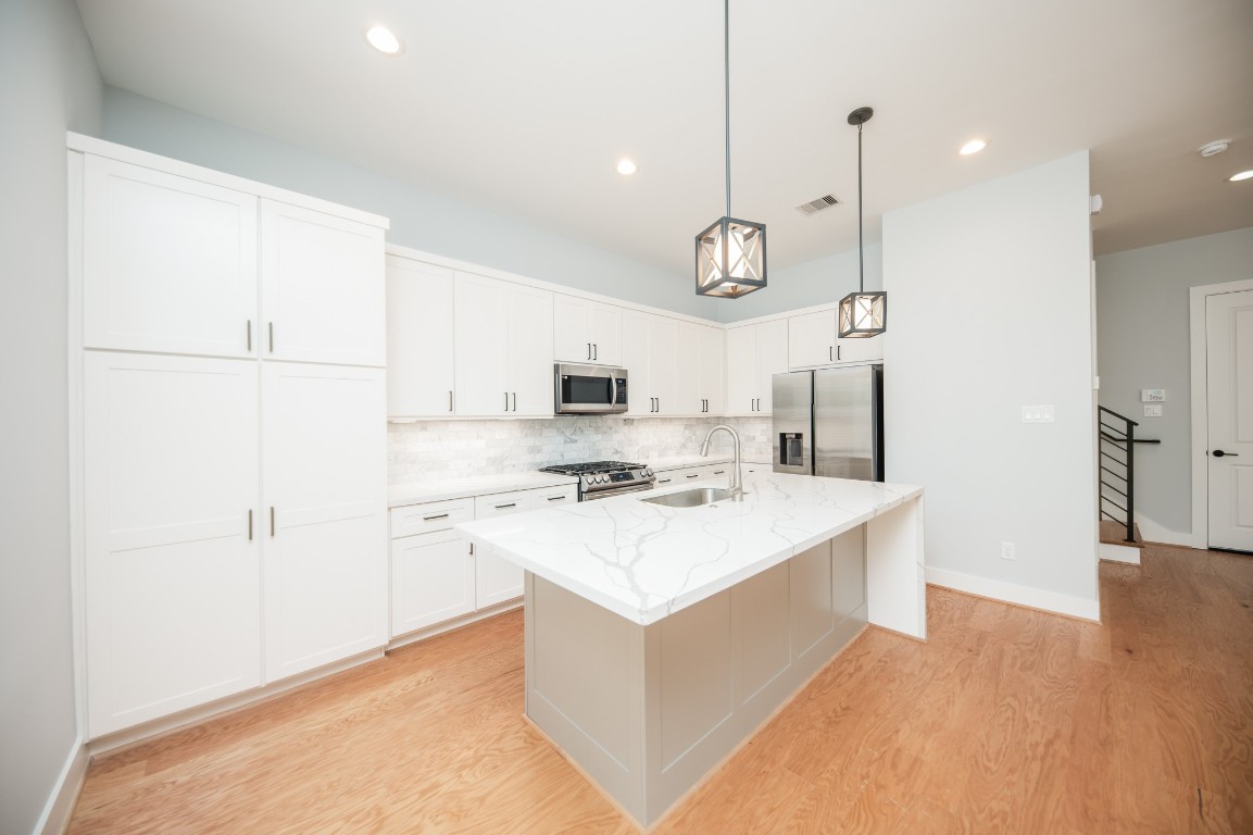 1860 West Tidwell Road Houston, TX 77091 - Photo 11 of 32 a kitchen with a stove a refrigerator a sink and white cabinets with wooden floor
