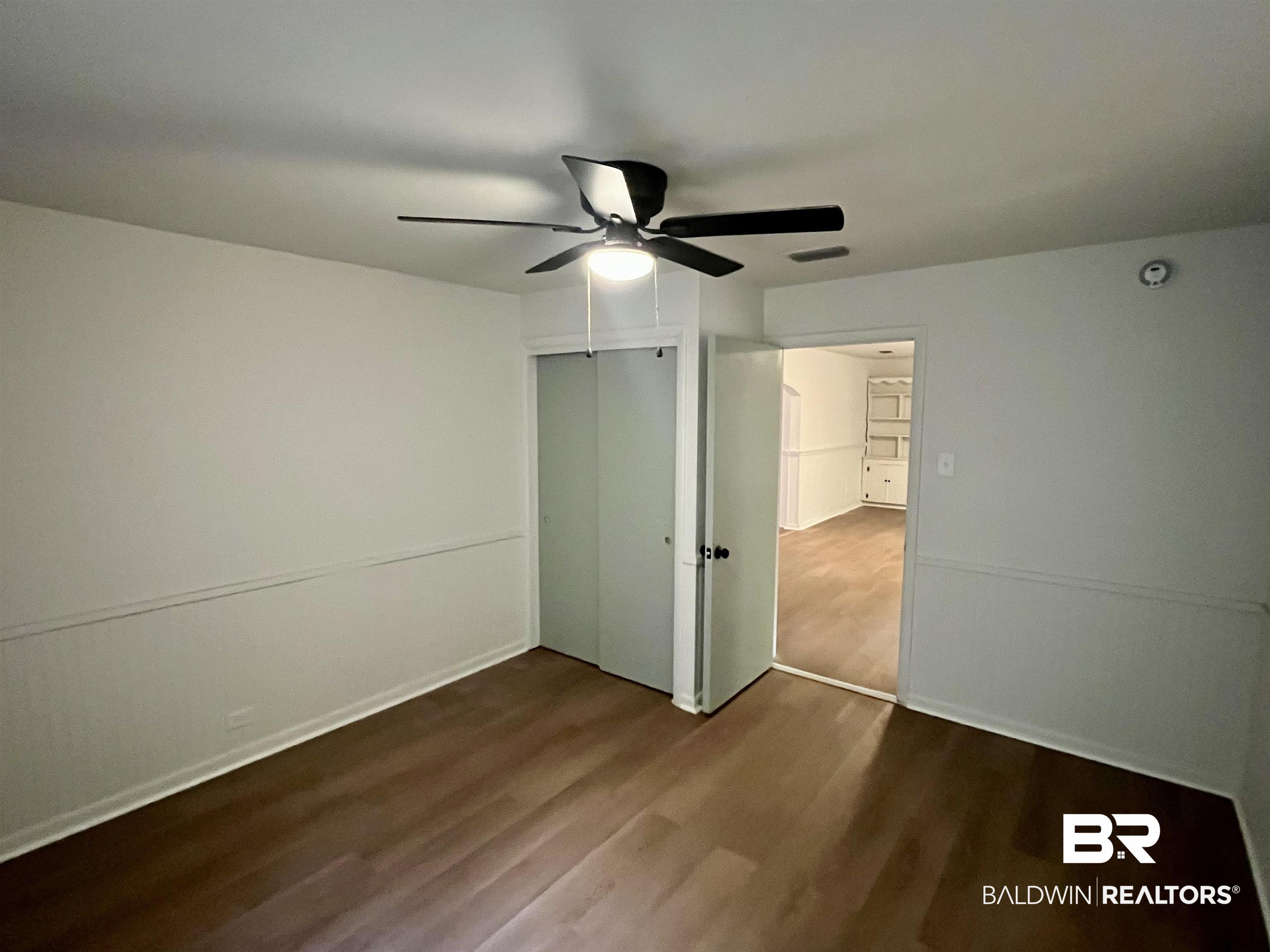 3105 Bryant Road Mobile, AL 36605 - Photo 30 of 39 Interior room featuring wood-finish flooring, white walls with wainscoting, and a ceiling fan with integrated lighting