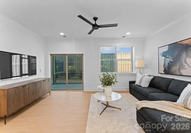 a living room with furniture ceiling fan and a large window