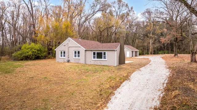 a view of house with backyard and trees in the background
