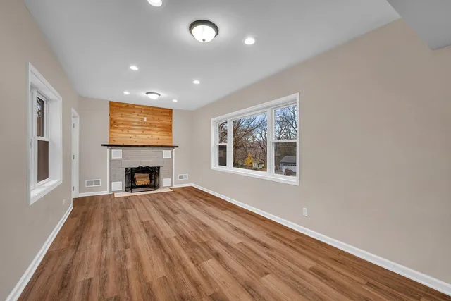 a view of empty room with wooden floor and fireplace