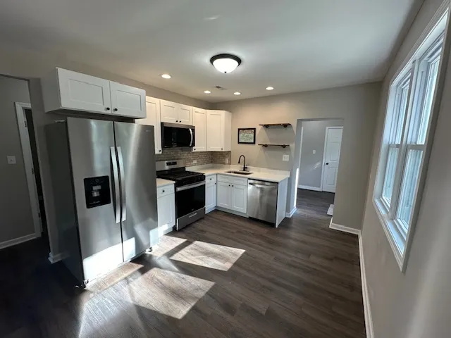 a kitchen with stainless steel appliances granite countertop a refrigerator stove and wooden floor