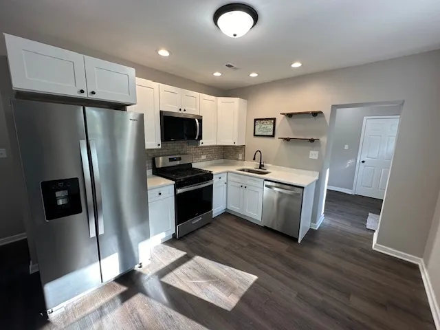 a kitchen with stainless steel appliances a stove a sink a refrigerator a microwave a cabinets and wooden floor