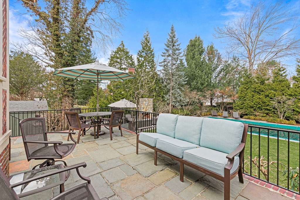 409 Heath Street Brookline, MA 02467 - Photo 28 of 29 a view of a patio with a table and chairs under an umbrella with large trees