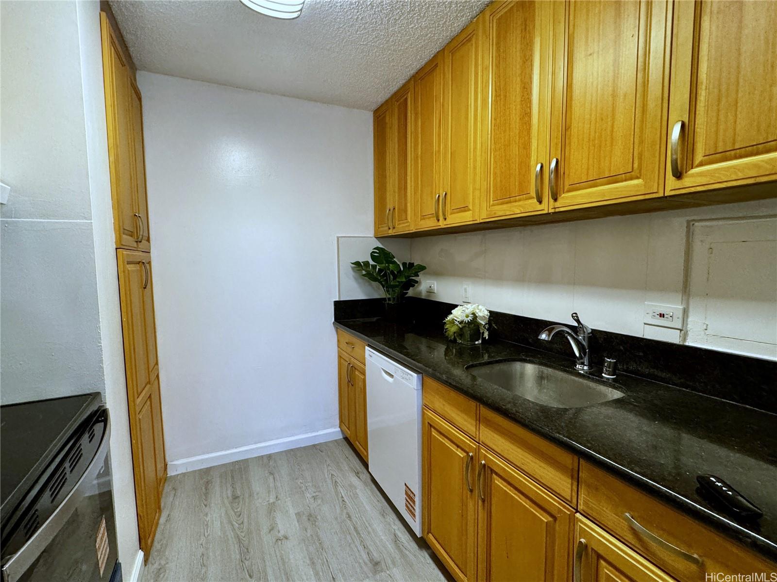 98-1042 Moanalua Road, Unit 2201 Aiea, HI 96701 - Photo 6 of 19 a kitchen with granite countertop stainless steel appliances a sink a stove and a microwave