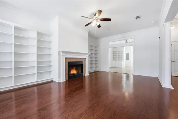 a view of an empty room with a fireplace and wooden floor