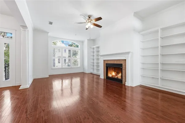 a view of an empty room with wooden floor fireplace and a window
