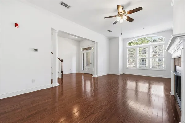 a view of an empty room with wooden floor and a window