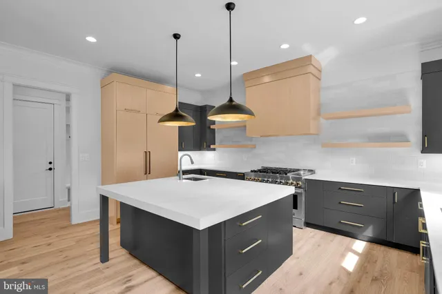 a kitchen with a stove a sink a center island and wooden floor