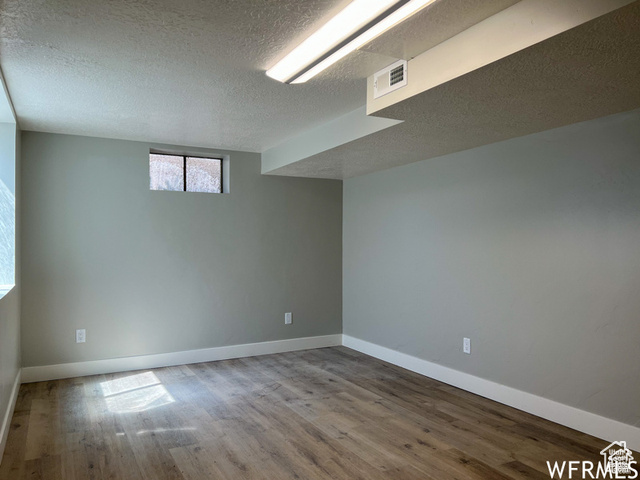 702 North 100 West Logan, UT 84321 - Photo 56 of 58 Below grade area featuring baseboards, visible vents, a textured ceiling, and wood finished floors