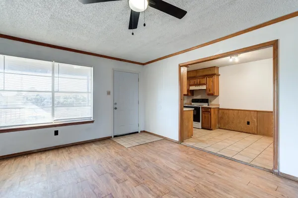 an empty room with wooden floor a ceiling fan and windows