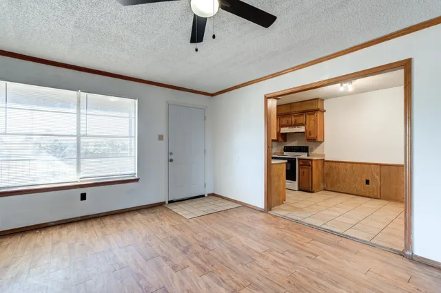 an empty room with wooden floor a ceiling fan and windows