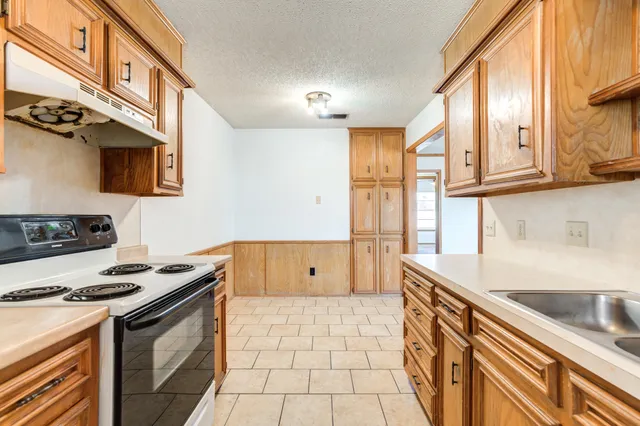 a view of a refrigerator in kitchen and an empty room in wooden floor