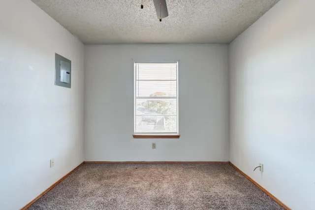 an empty room with a window and a fan