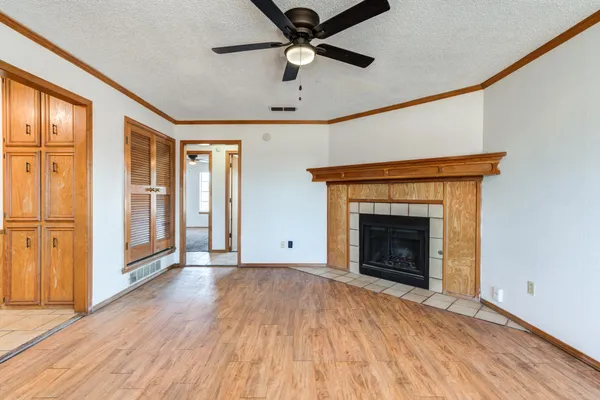 a view of an empty room with a fireplace and a ceiling fan